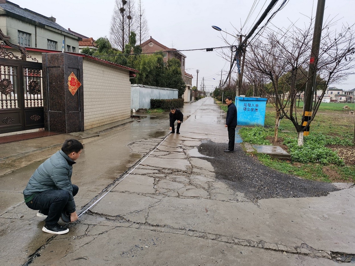 长旺村党委副书记丁宏基与建设公司人员测量路面需要修缮面积1.jpg